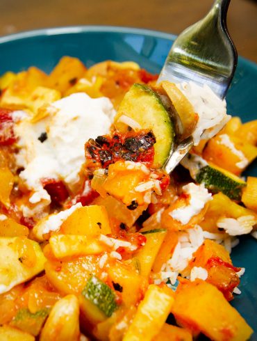 vegetable curry with basmati rice plated in a blue bowl with a dollop of Greek yogurt